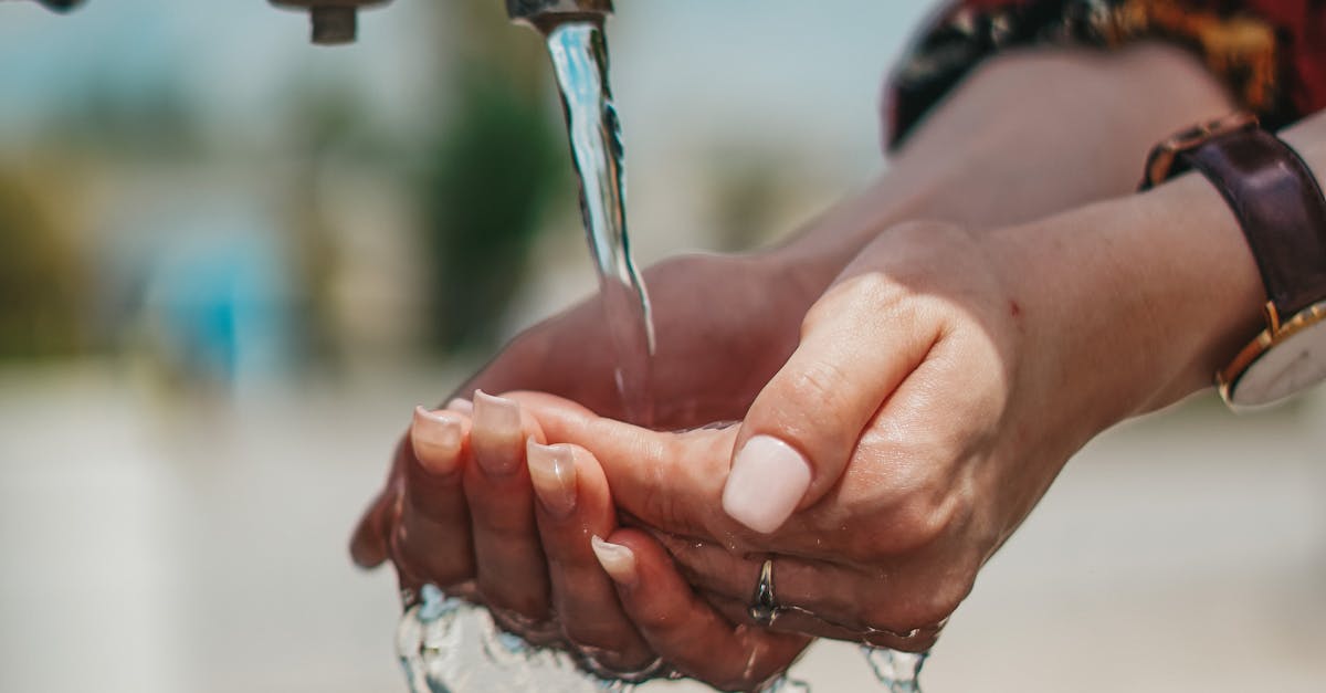 Refreshing scene of a woman washing hands at an outdoor tap on a sunny day.